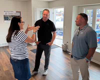 Chris Cournoyer, Chad Squires, and David Miller standing in a circle engaged in conversation in the middle of the Homes for Iowa house